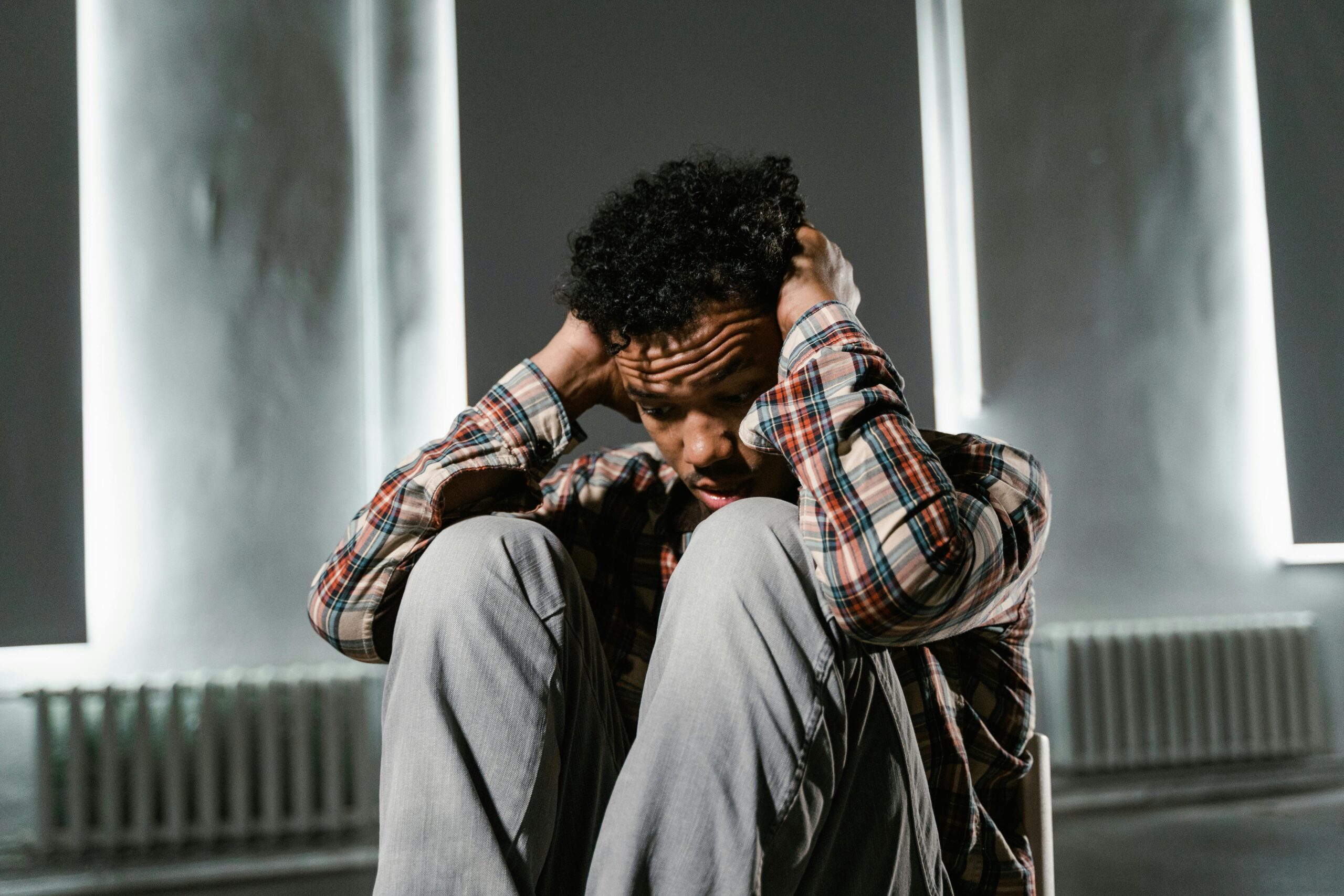 Anxious man sitting alone, distressed after receiving threatening messages from a loan app recovery agent