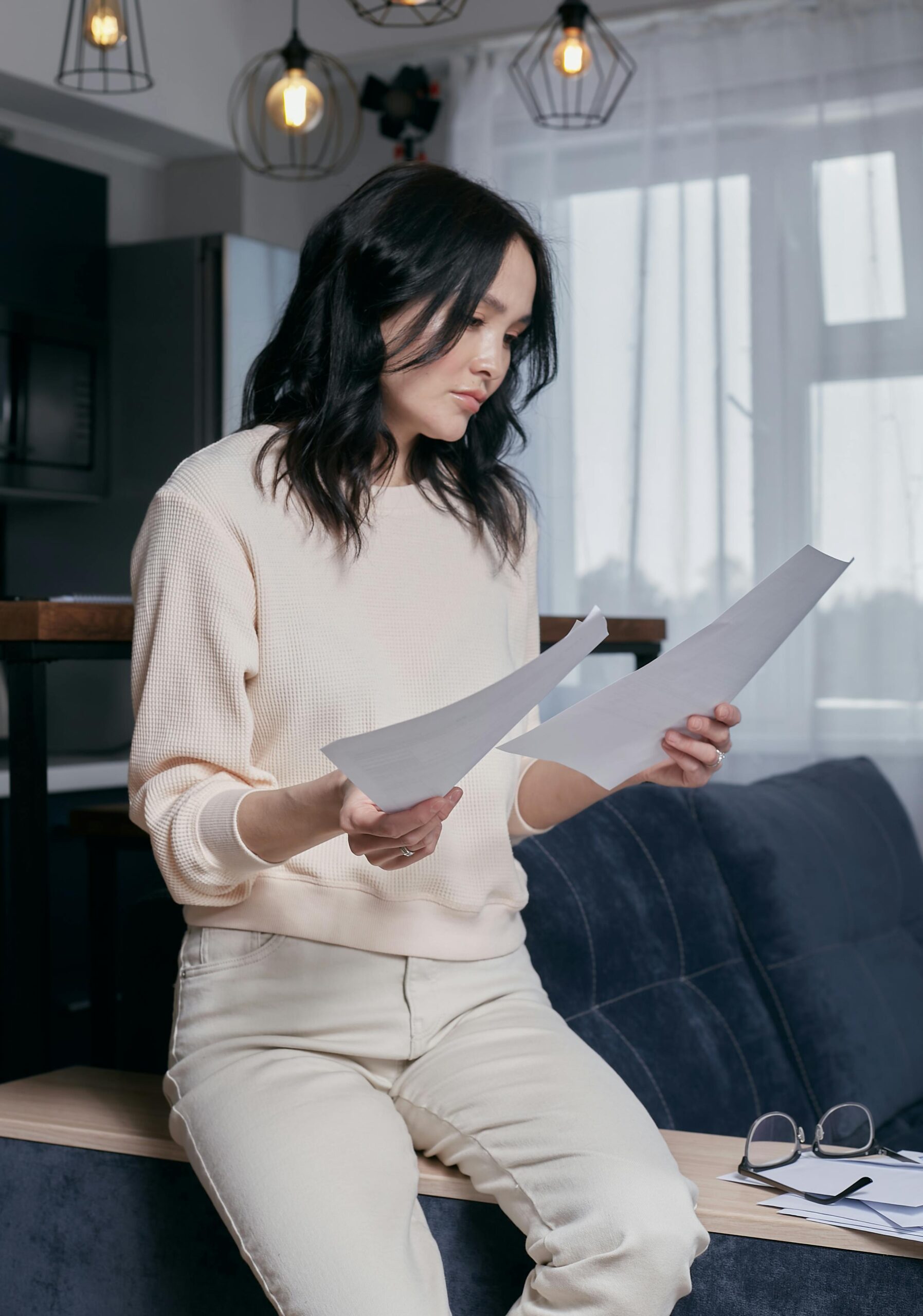Asian woman carefully reviewing loan app terms and documents at home before applying — borrower safety India