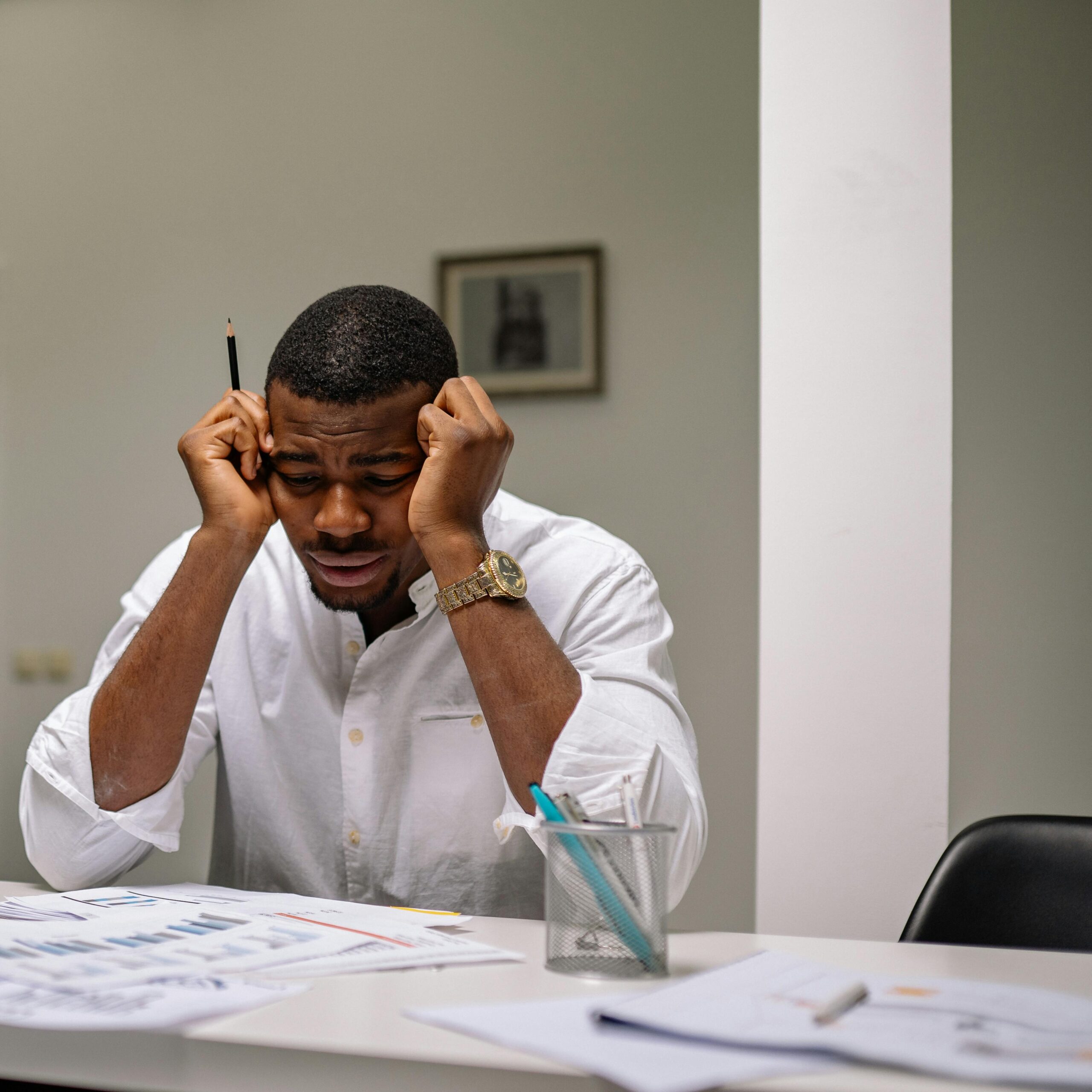 Man stressed at his desk after realising he cannot meet two simultaneous loan repayment deadlines